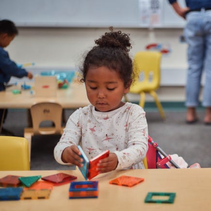 A young child focuses on buiding blocks in a classroom.