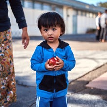 A young child eating an apple in a schoolyard.