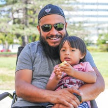 A father smiling while cuddling his young child.